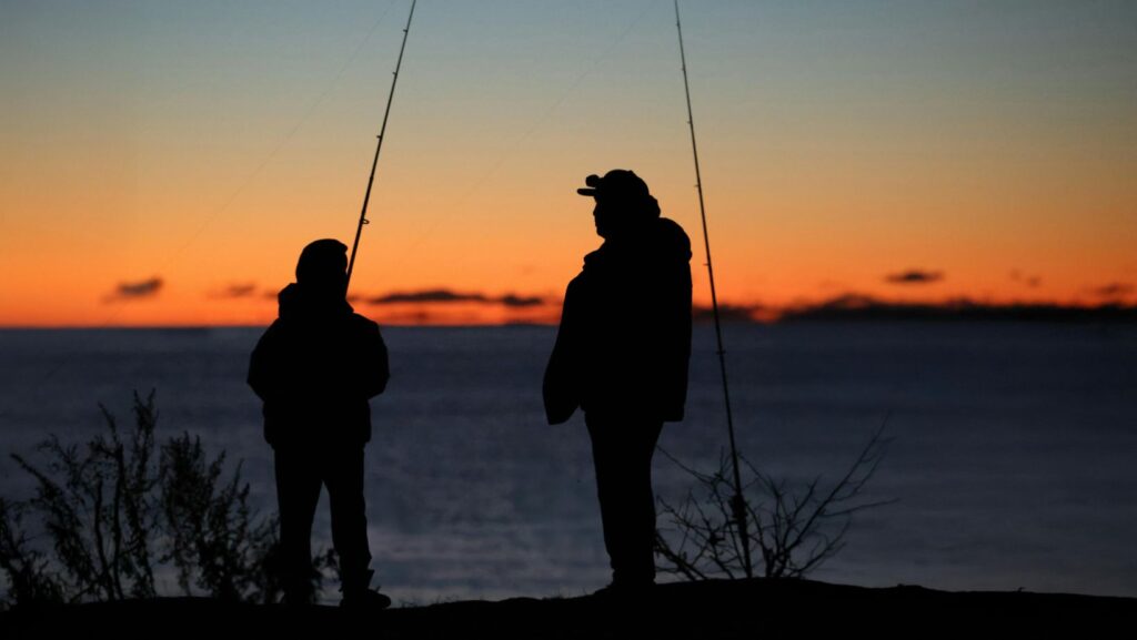 father and son fishing at sunset